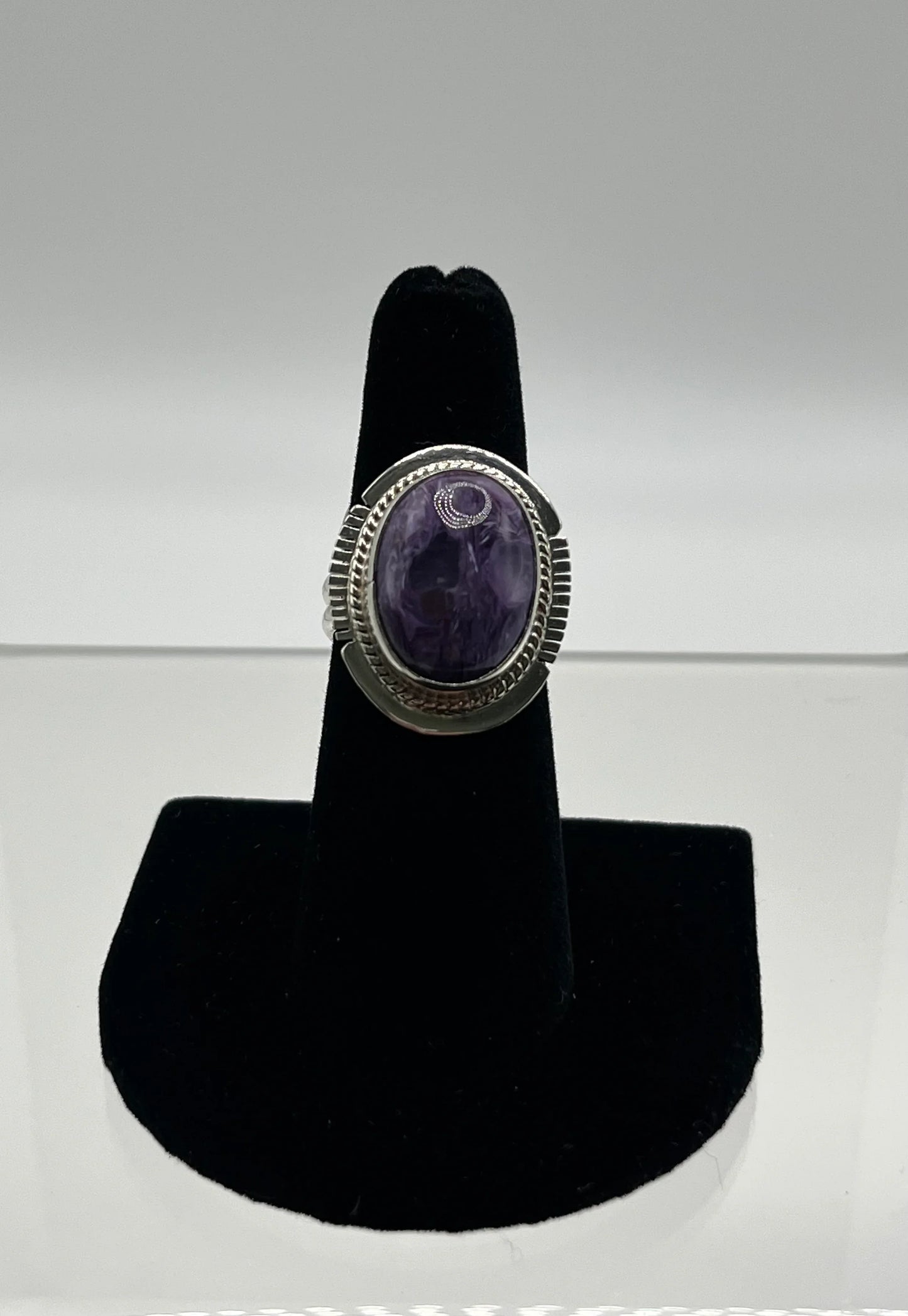Amethyst oval ring with silver crescent moon design, displayed on black velvet stand.
