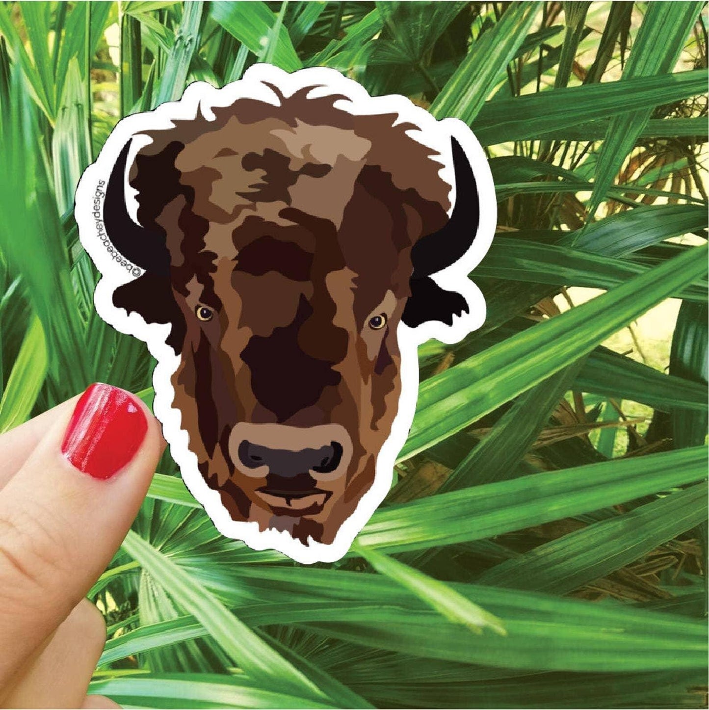 Bison head sticker held against green foliage, Native art inspired design