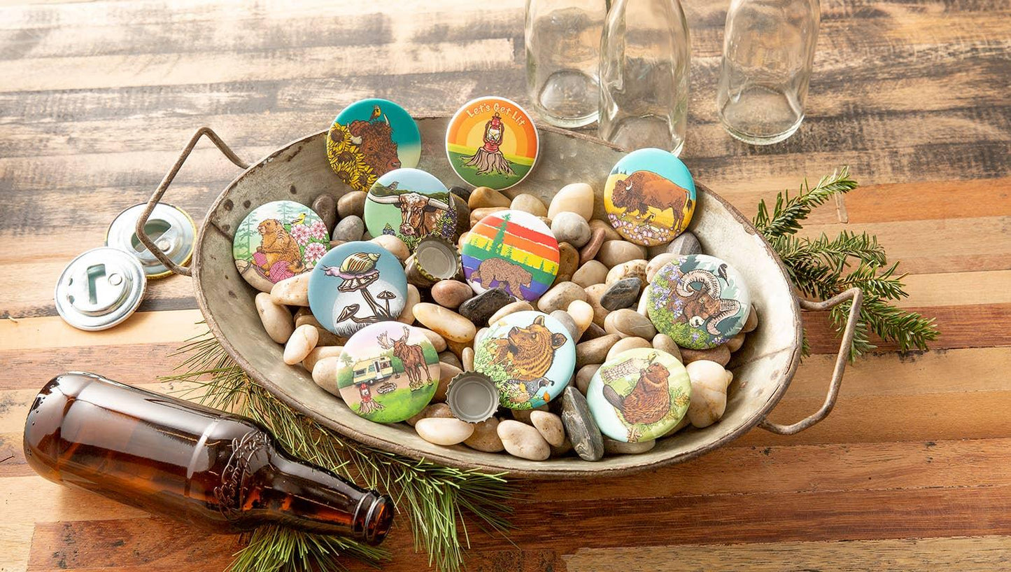 Colorful nature-themed pins with wildlife designs in a rustic metal tray on wooden table