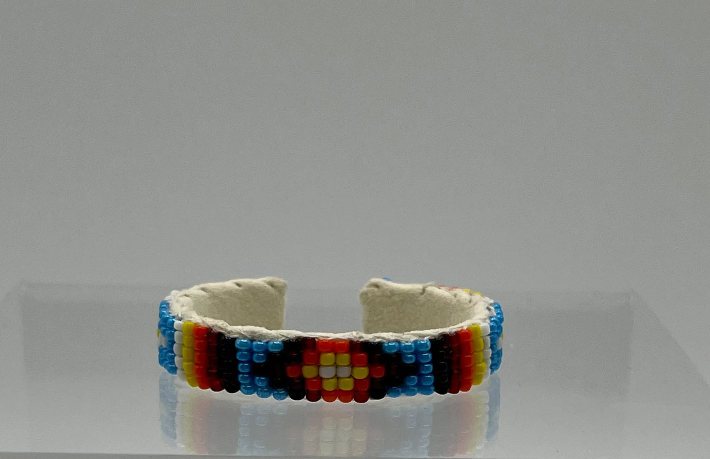 Handcrafted Native American beaded bracelet with colorful geometric patterns on leather cuff