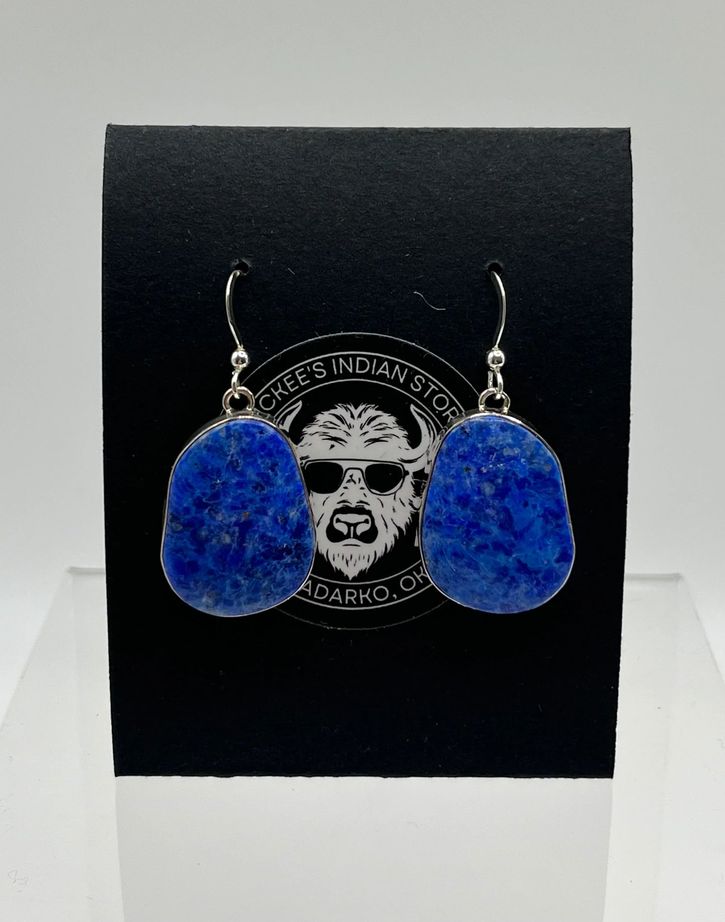 Blue lapis lazuli drop earrings with silver hooks, displayed on black card with store logo