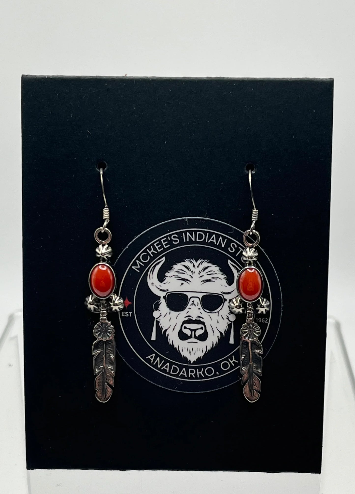 Native American style earrings with red stone and feather charms, displayed on black card with buffalo logo
