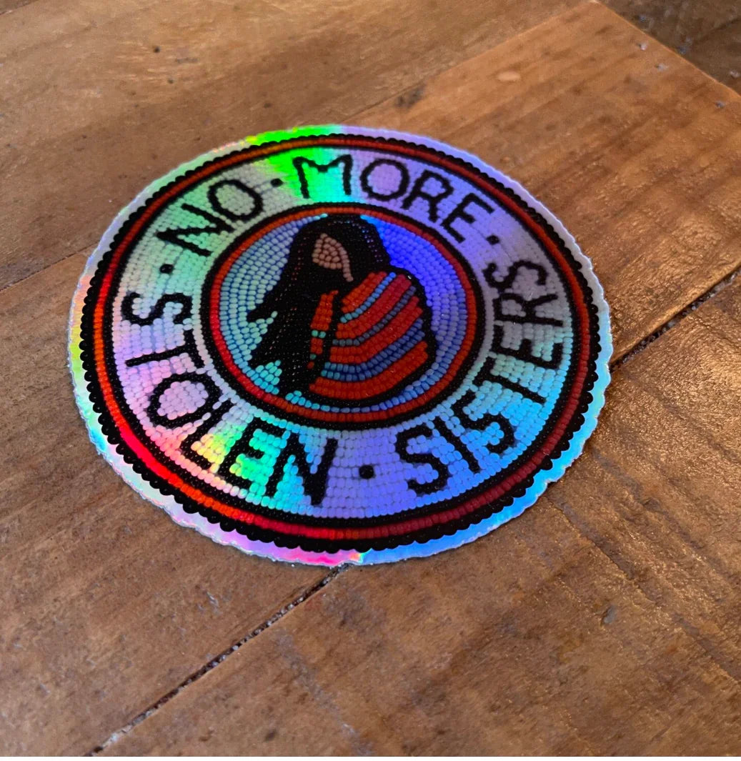 Hand-beaded Native art patch with 'No More Stolen Sisters' text, vibrant colors, on wooden surface