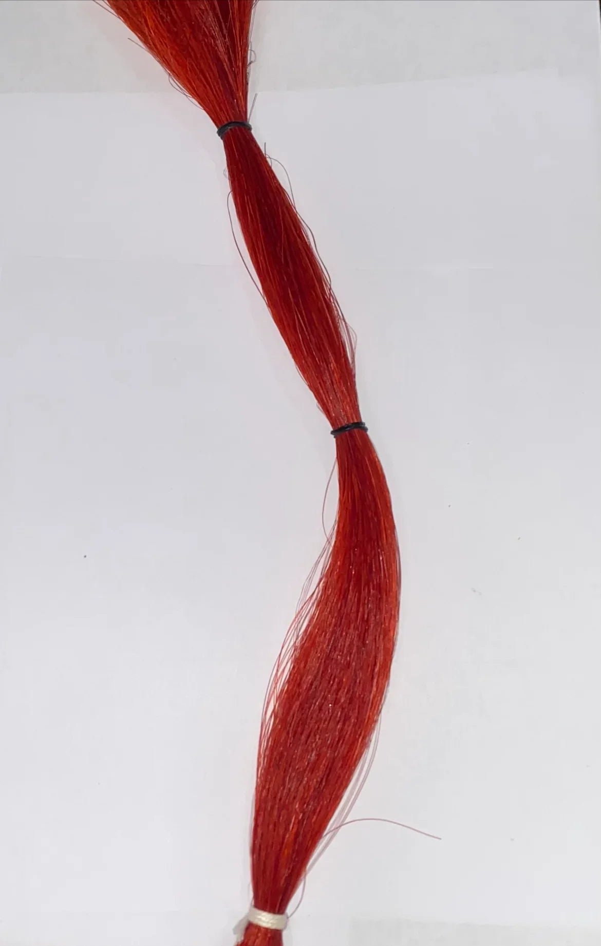 Vibrant red synthetic hair bundle for Native American crafts and traditional regalia, tied with bands
