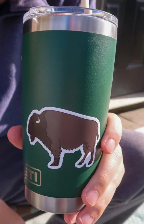 Green insulated tumbler with bison silhouette, held in hand, ideal for Native art supplies and crafts.