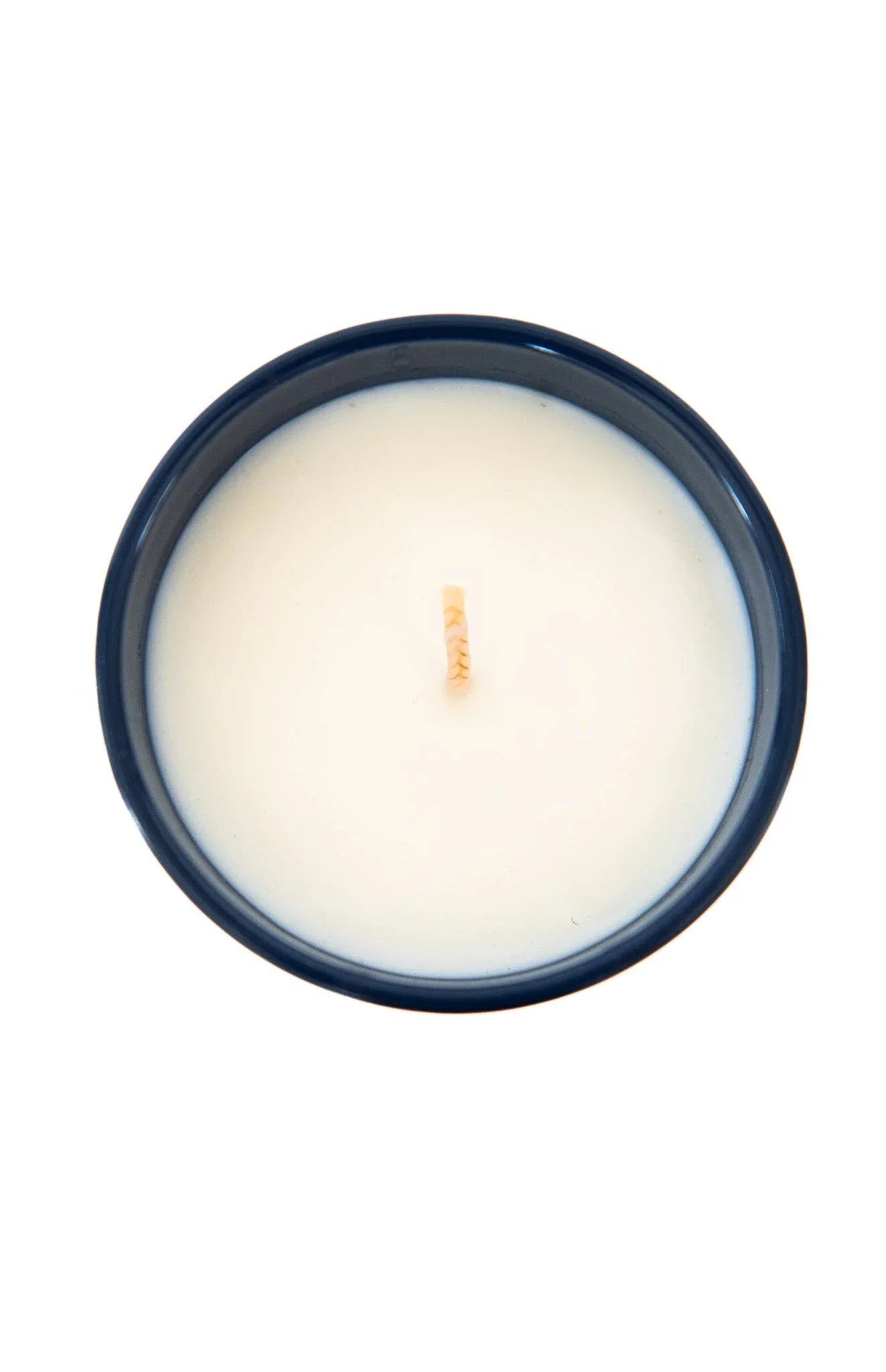 White candle in navy blue ceramic holder, top view