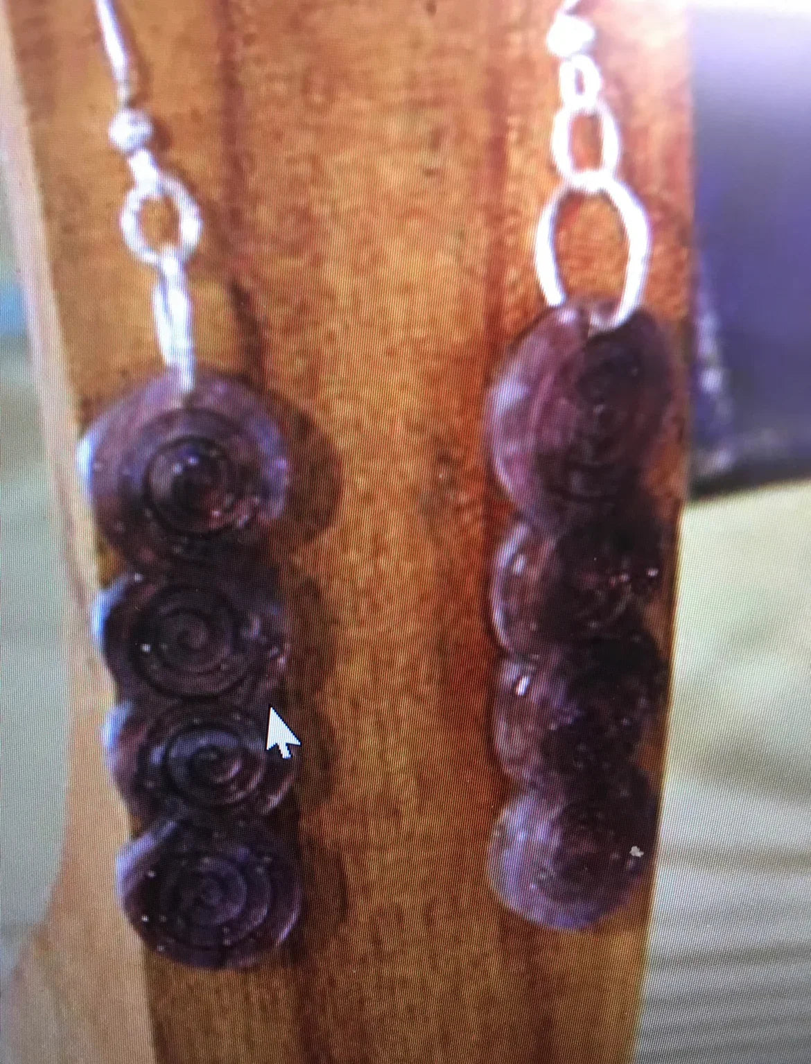 Handcrafted Native American spiral bead earrings with silver chain, displayed on wood