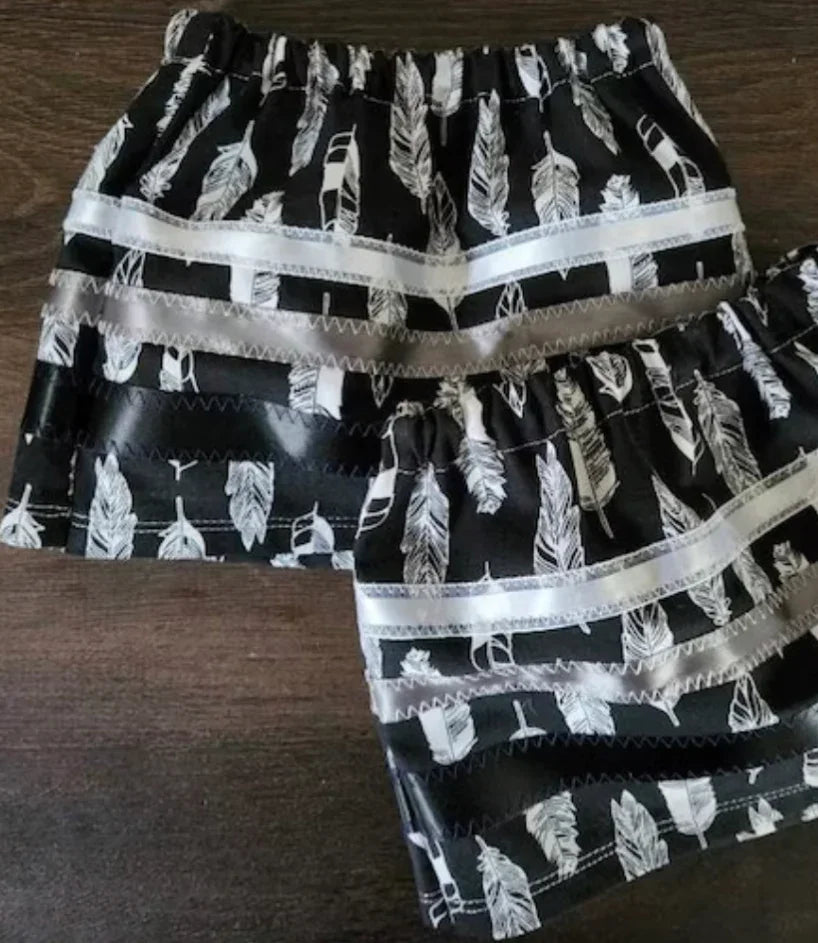 Black and white feather-patterned Native American dance skirts with satin trim, ideal for traditional regalia.