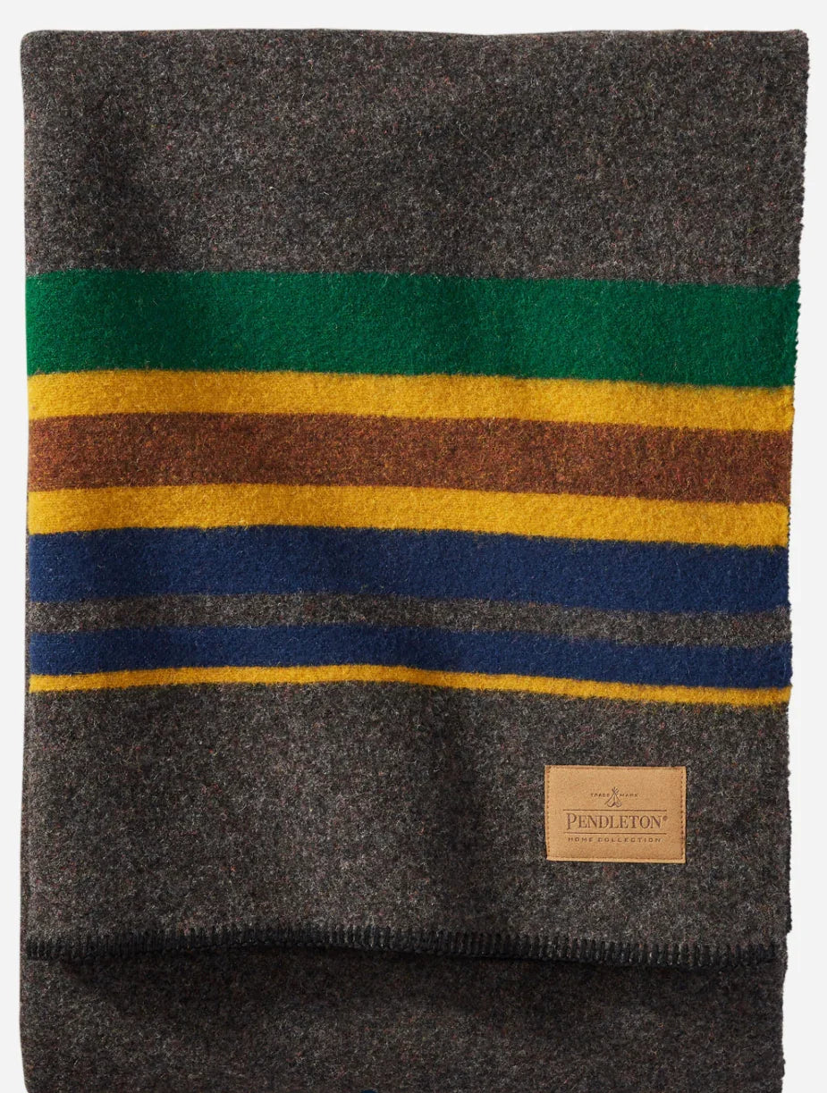 Pendleton wool blanket with green, yellow, brown, and blue stripes, cozy for Native art and craft spaces