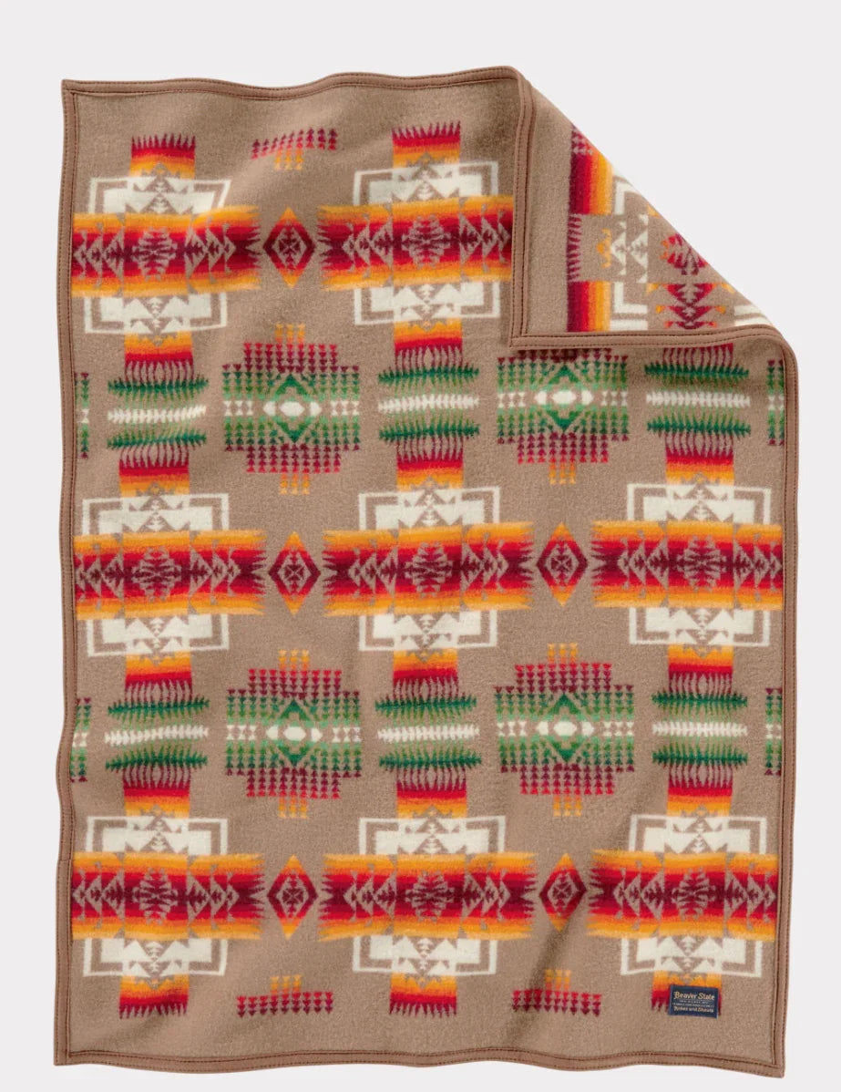 Native American patterned blanket with geometric designs in red, orange, green, and white on tan background
