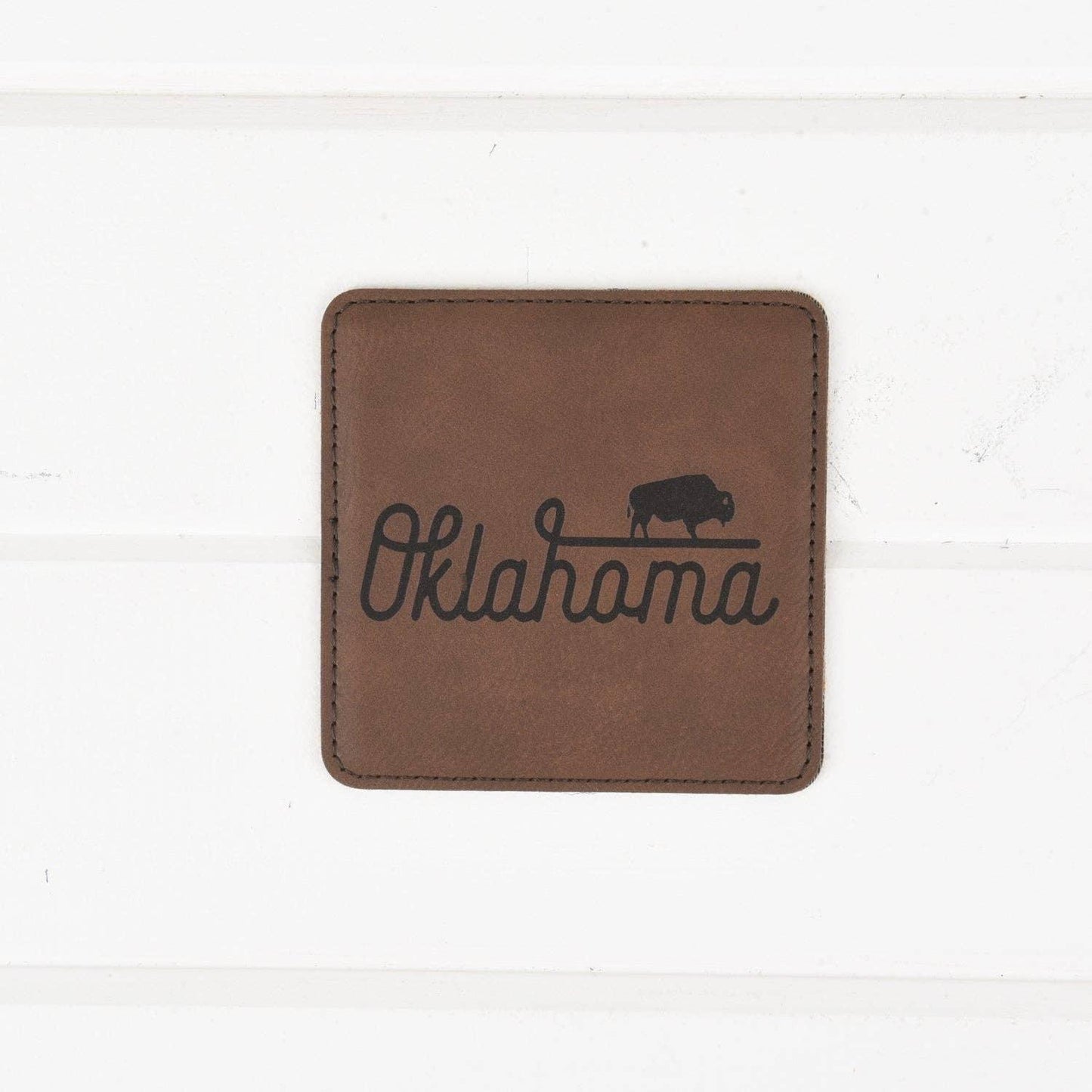 Brown leather coaster with Oklahoma script and bison silhouette, perfect for Native art enthusiasts.